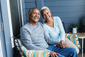 A couple smiling and sitting on a porch. Links to Beneficiary Designations
